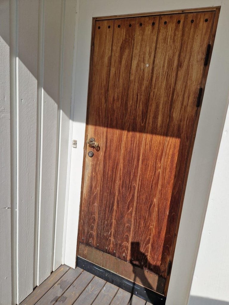 Wood front door in Sarasota with dark moisture-related staining near the lower panels